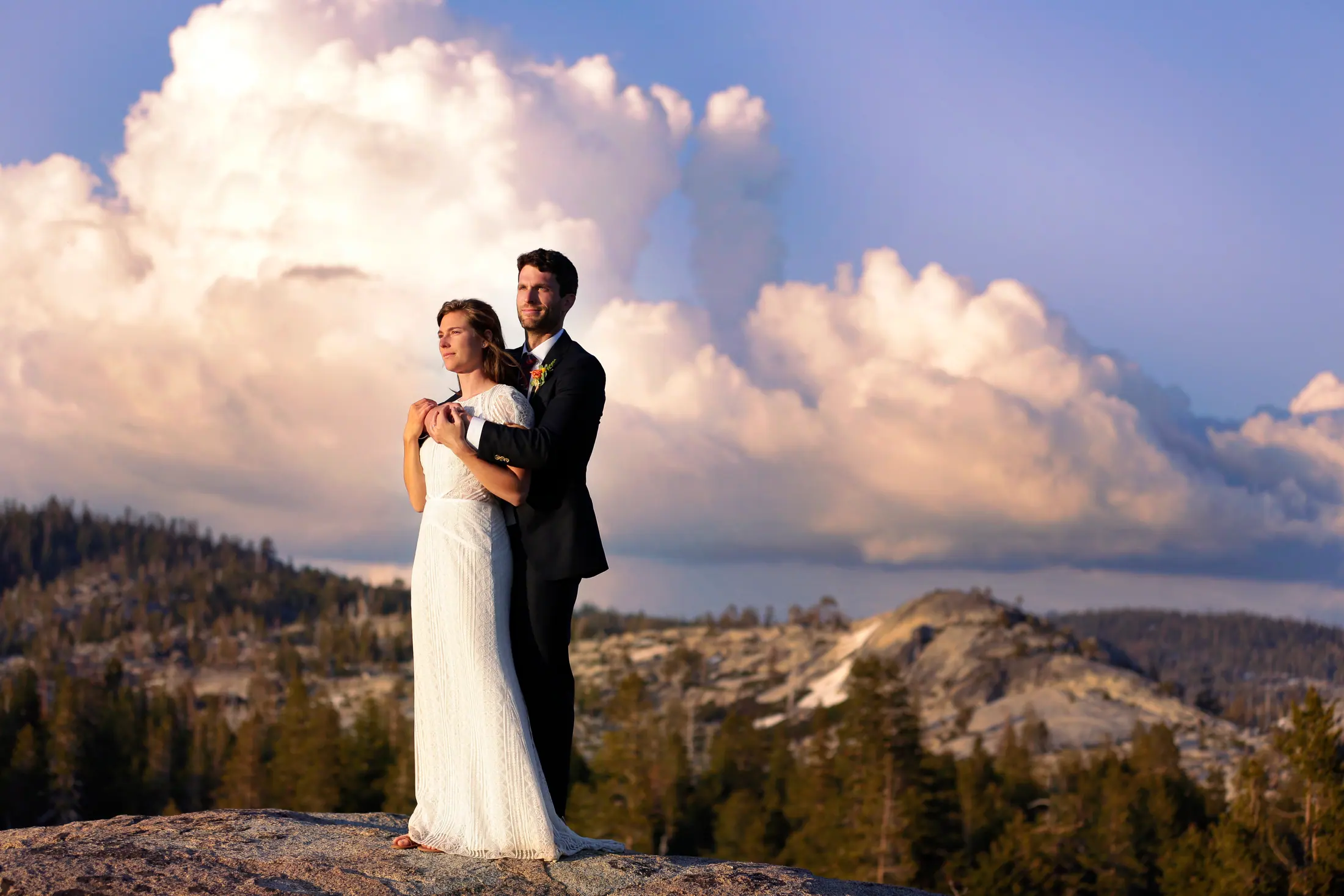 A couple on the granite under big clouds.