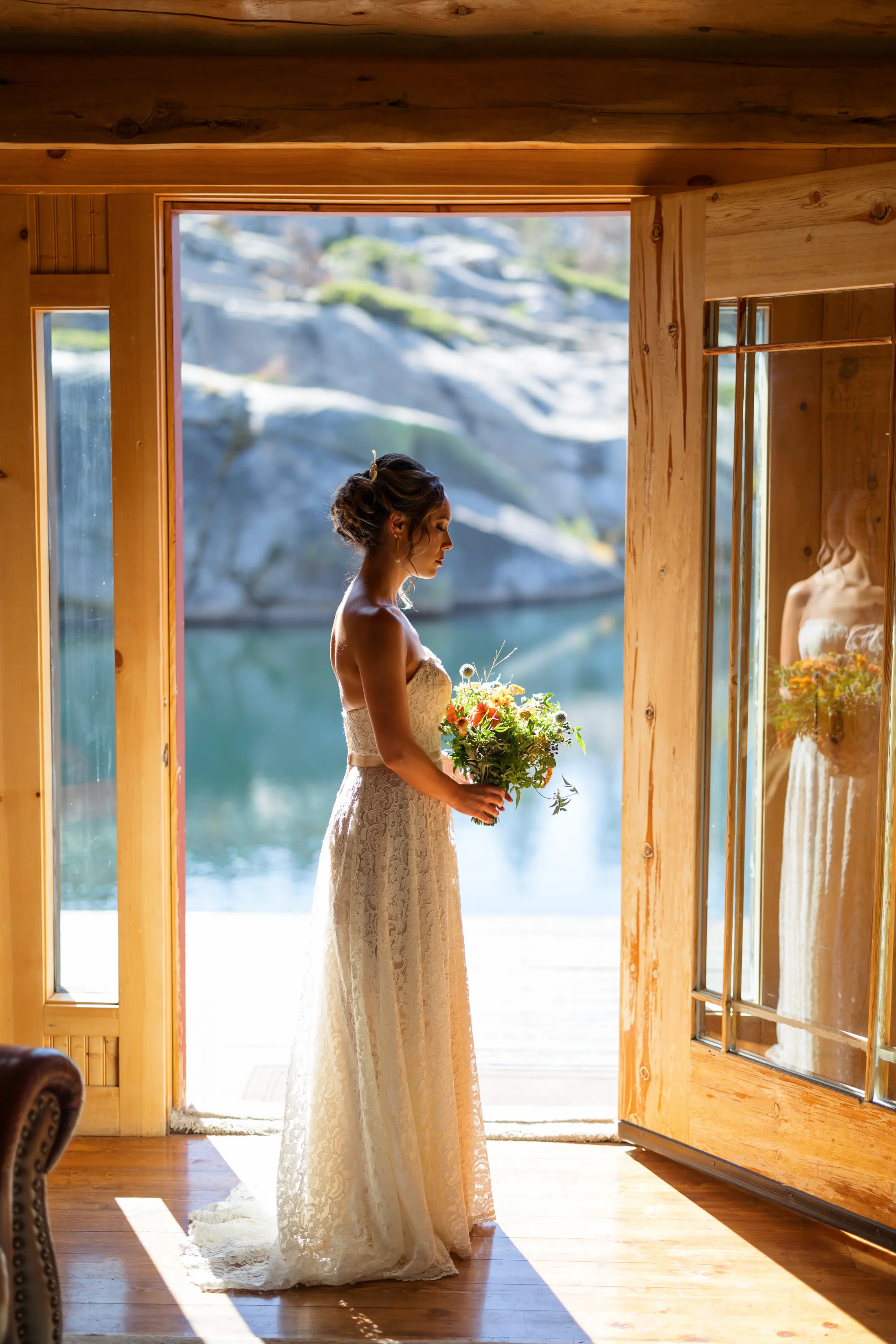 A bride in the lodge doorway, the lake behind her.