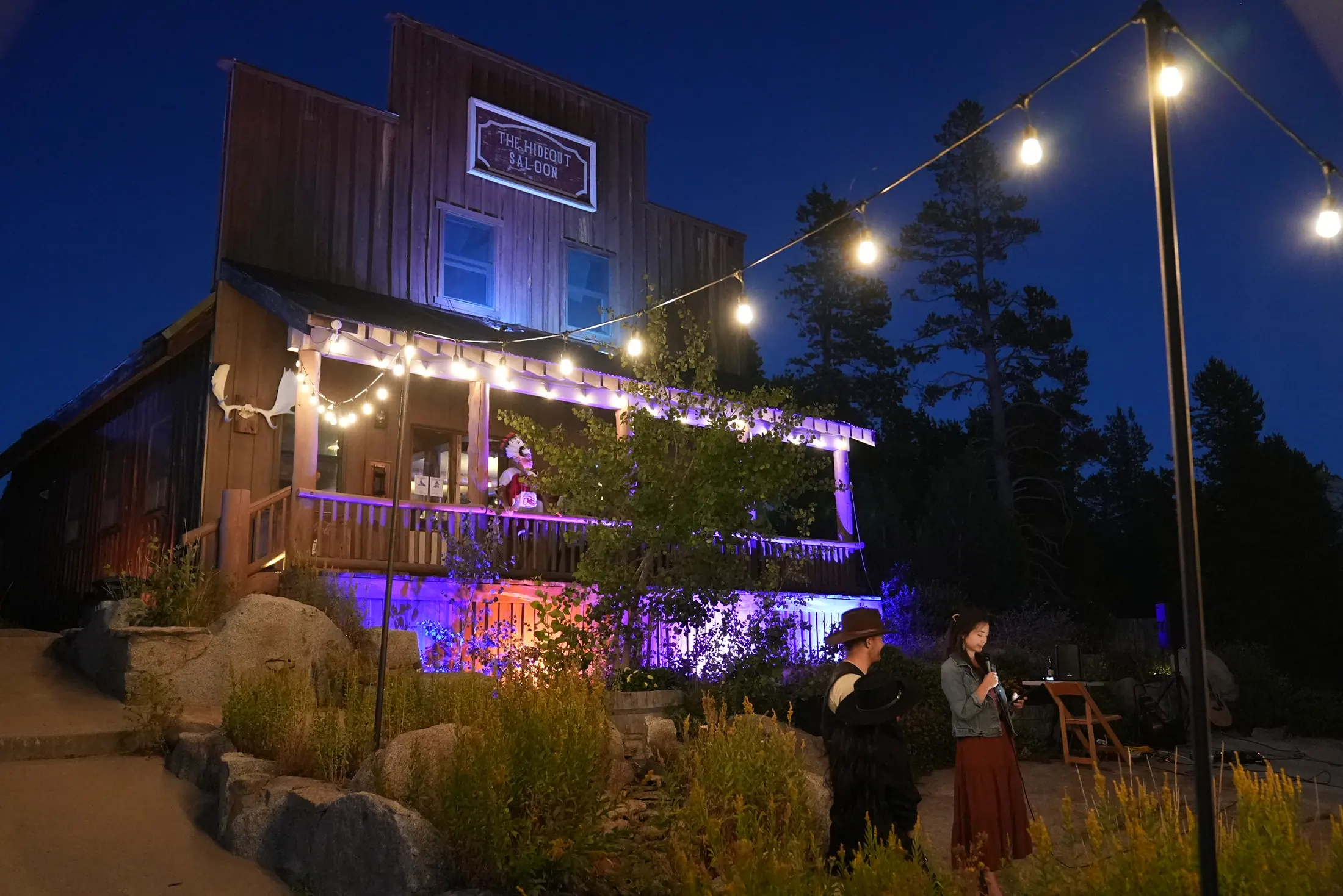 The saloon lit at night with guests on the boardwalk.