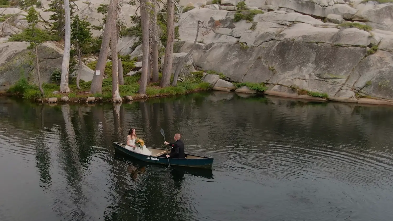 Still from the film — the lodge reflected in the private lake at first light.